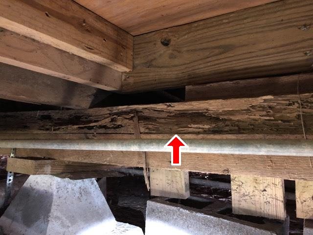 Rotted floor joist in a crawlspace, marked with a red arrow